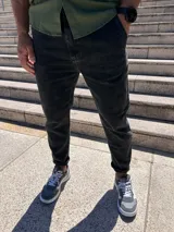 Pantalón de jean negro gastado, corte slouchy, con bolsillos delanteros y traseros, y ruedo arremangado.