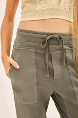 Pantalón tipo babucha color verde militar, con ajuste en tobillos y cintura regulable con cordón a tono. Confeccionado en gabardina elastizada, la cintura y los puños están realizados en flame. Cuenta con bolsillos diagonales en el frente y bolsillos con solapa y botón en la parte trasera.