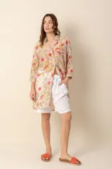 Camisa larga estampada con flores rojas y amarillas sobre fondo beige, de mangas 3/4 y corte holgado.