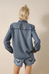 Camisa de tencel celeste con bordado de lentejuelas doradas, calce recto, manga larga y cuello camisero.