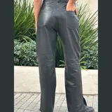 Pantalón de cuero negro de tiro medio y pierna recta con tajo en el ruedo.