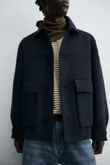 Abrigo relaxed fit confeccionado en tejido con mezcla de lana. Cuello solapa y manga larga acabada en puño con botón. Bolsillos con solapa en cadera. Cierre frontal de botonadura.