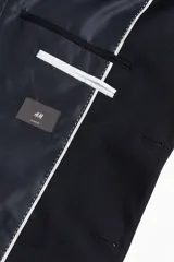 Blazer azul marino de corte slim fit, con solapas de muesca finas, botonadura sencilla con dos botones, bolsillo superior, bolsillos delanteros con solapa, tres bolsillos interiores, botones decorativos en los puños y abertura trasera.