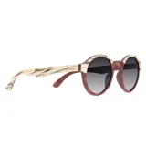 Lentes de sol Indie modelo Hill con montura redonda de madera color marrón y beige, y lentes grises degradadas.