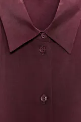 Camisa marrón de seda 100% con cuello solapa, manga larga con puños abotonados, bajo asimétrico redondeado y cierre frontal con botones.