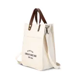 Bolsa matera de tela canvas color beige, con bolsillo frontal, división interna para termo y mate. Incluye correa de galón desmontable y asa de mano removible con broches.