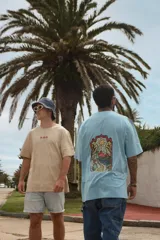 Remera blanca de manga corta con cuello redondo y estampado de tres hongos rojos y la palabra "Tuya" en el frente.