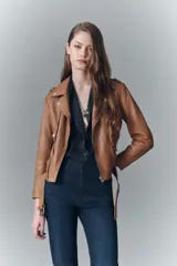 Campera negra de cuero ovino, estilo rocker, con cinturón, charreteras y solapas. Tiene cierres y detalles metálicos en frente y espalda.