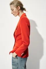 Blazer color rojo con cuello solapa, manga larga con hombreras, bolsillos delanteros con solapa y cierre frontal con botones dorados.