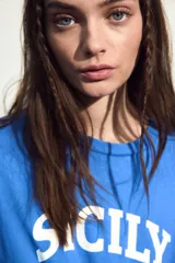 Remera azul de algodón con cuello redondo y estampado frontal con la palabra "Sicily" en color blanco.