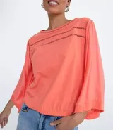 Blusa color salmón con escote redondo, mangas 3/4 amplias y ajuste frontal. Confeccionada en tejido laise.