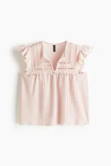 Top sin mangas color rosa pálido con textura arrugada, escote en V con tiras para atar y detalles de encaje calado en el canesú. Presenta mangas cortas con volados y corte holgado con costura fruncida bajo el busto.