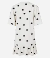 Vestido corto evasé color crema con estampado de soles negros, cuello redondo con lazo, mangas cortas y bajo con volantes.
