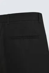 Pantalón negro relaxed fit confeccionado en tejido con algodón, lino y lyocell. Cintura con detalle de pliegues frontales dobles, bolsillos delanteros y traseros. Cierre frontal con cremallera y botón.
