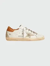 Zapatillas Golden Goose modelo Super Star, color blanco con estrella de gamuza gris, talón de cuero marrón y suela gastada.