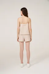 Conjunto de pijama de satén a rayas verticales color beige, compuesto por un top con breteles finos y escote en V, y un short de calce holgado.