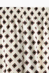 Pantalón de corte holgado con cintura elástica de tiro alto, bolsillos laterales discretos y piernas amplias.