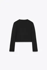 Blazer corta negra de cuello redondo y manga larga, con cierre frontal cruzado con botones dorados y falsos bolsillos delanteros.