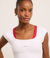 Remera cropped deportiva blanca de microfibra, con cuello redondo, manga corta y estampa lettering.