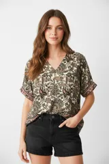 Blusa de poliéster estampada con diseño paisley en tonos beige, marrón y rosa. Tiene escote en V, mangas cortas y corte holgado.