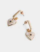 Aros argolla dorados con dije de corazón esmaltado en blanco, con un strass negro central y detalles de rayos en dorado.