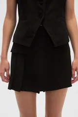 Minifalda negra con corte asimétrico y detalle de tabla en el frente.