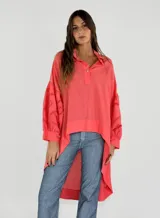 Blusa color coral con cuello camisero, mangas largas con detalles de calado y bajo irregular.