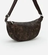 Cartera bandolera mediana de poliuretano marrón con efecto desteñido, forma de media luna y asa larga ajustable de gorgorón.