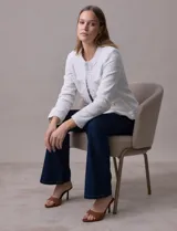 Chaqueta Nanette de tejido tweed color blanco, con escote mao, abertura central y bolsillos delanteros. Presenta apliques de botones perlados en los puños y terminación desflecada.