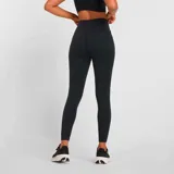 Calza larga de training New Balance modelo Harmony High Rise, color negro, con cintura alta y logo reflectivo en la pierna.