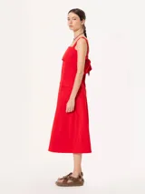 Vestido midi rojo de poplin con lycra, corte evasé, breteles anchos, bolsillos laterales y tajo frontal. Se ajusta en la espalda con un lazo.