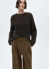 Camisa marrón con rayas verticales finas, de corte oversize, manga larga con puños abotonados, cuello camisero, bolsillo de parche en el pecho y cierre frontal con botones.