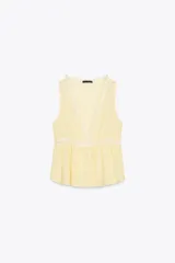 Blusa amarilla sin mangas con escote en pico y detalle de puntillas blancas. Cierre frontal con botones.