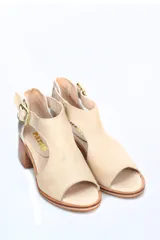 Sandalia de mujer color beige con puntera abierta y tira en forma de T. Posee tira de ajuste con hebilla en el tobillo y detalle de cuero metalizado plateado en el talón. El taco es ancho y de madera.