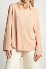 Camisa color salmón de corte oversize, confeccionada en lino y viscosa, con cuello clásico, cierre frontal con botones y mangas largas con puños anchos.