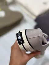 Zapatillas bajas de lona color blanco, con cordones marrones, puntera de goma y base blanca.