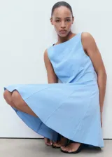 Vestido corto sin mangas color celeste, con cuello barco, diseño de tablas y cierre de cremallera en la espalda.