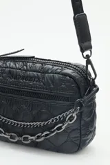 Bandolera negra de nylon matelassé con correa regulable, avíos metálicos, llavero de corazón y dijes desmontables.