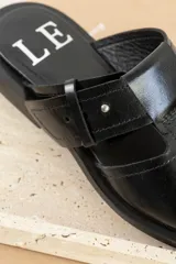 Sandalias de cuero negro con diseño abierto y correa ajustable.