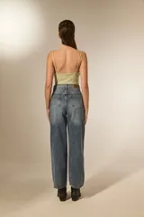 Pantalón de jean azul lavado, tiro alto, corte recto y largo. Presenta un patrón de rombos cosidos con hilo blanco o strass a lo largo de toda la prenda.