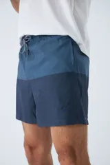 Short de baño celeste con estampado de líneas curvas en azul. Cuenta con cintura elástica con cordón ajustable, dos bolsillos laterales, un bolsillo trasero, suspensor interno y logo bordado.