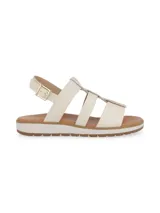 Sandalia de cuero color crema, con tiras cruzadas y detalle de flecos marrones en la parte delantera.