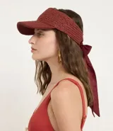 Visera de playa para mujer confeccionada en fibra de papel con textura trenzada. Presenta un diseño de ala ancha y un lazo de tela largo en la parte posterior para anudar.