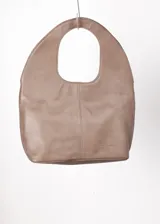 Bolso tote negro de cuero con manija circular rígida.
