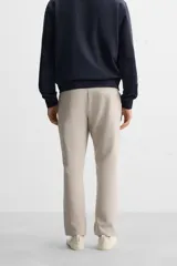 Pantalón de jogging color beige confeccionado en tejido de mezcla de algodón. Cuenta con cintura elástica ajustable con cordón, bolsillos frontales y traseros.