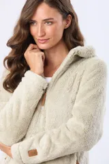 Campera de sherpa suave color beige, con capucha, cierre frontal con detalles en cuero y bolsillos laterales.