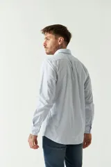 Camisa celeste a rayas rojas de hombre, manga larga, con bolsillo y logo bordado.