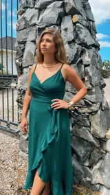 Vestido largo blanco de crepé con escote en V, breteles finos y corte envolvente con volados en el ruedo.