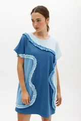 Vestido corto de algodón con bloques de color azul en diferentes tonos y volados ondulados que unen los bloques. Tiene cuello redondo y mangas cortas.