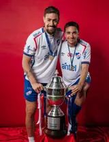 Camiseta de fútbol Umbro del Club Nacional de Football, modelo Home 2025. Diseño blanco con detalles en azul y rojo en cuello y mangas. Incluye logo de Umbro, escudo del club y sponsor Sarubbi en el frente.